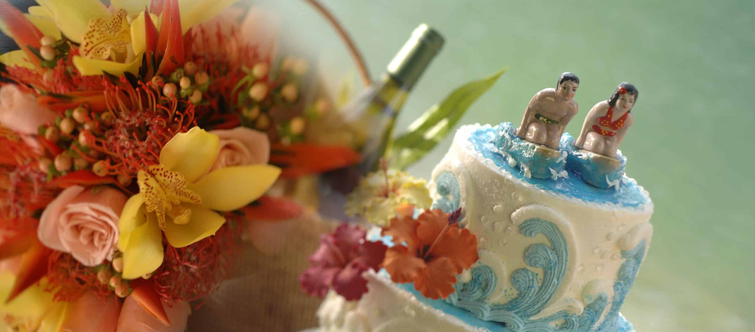 Wedding cake topped with a vintage couple on surfboards next to a bouquet a flowers and a bottle of wine