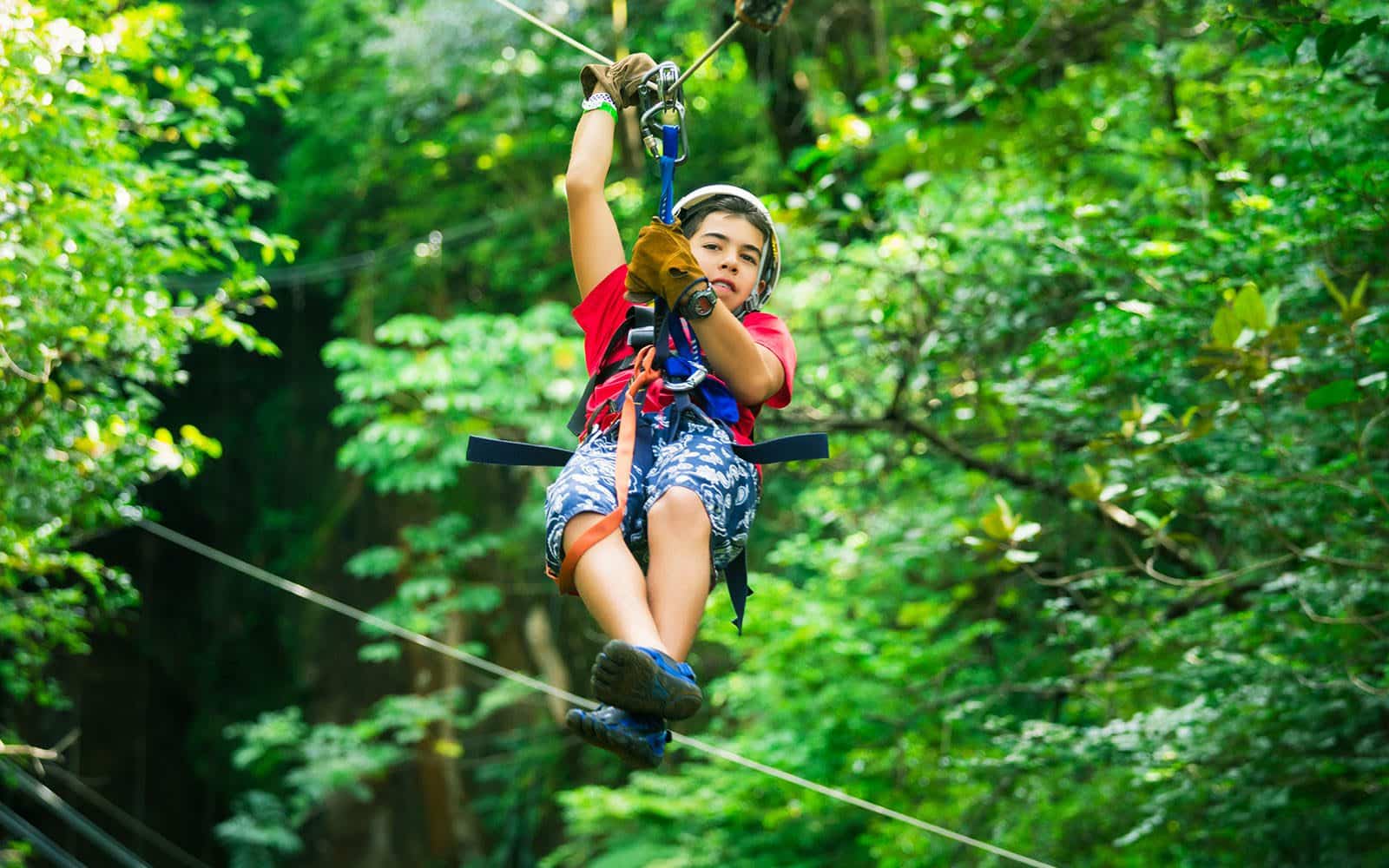 Adolescent boy riding a zipline through Oahu forest.