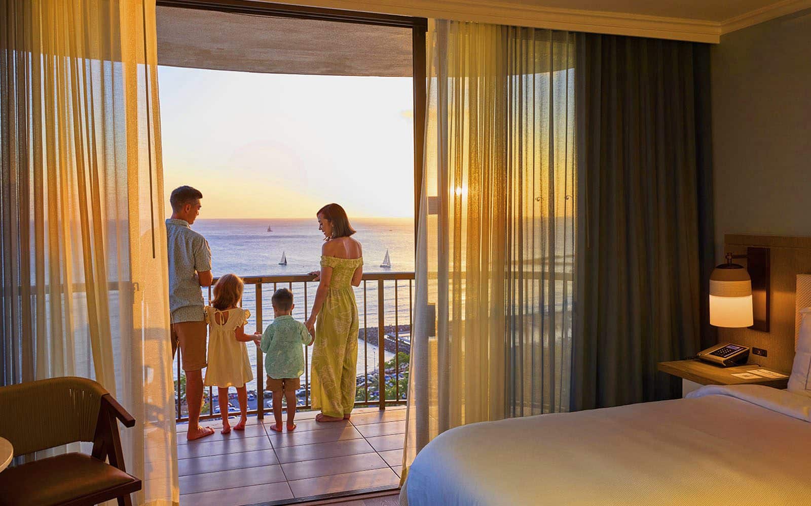 Family of four standing on the Rainbow Tower balcony at sunset.
