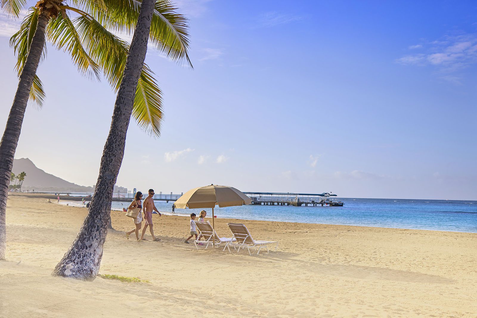 A family on the beach in front of the Hilton Hawaiian Village