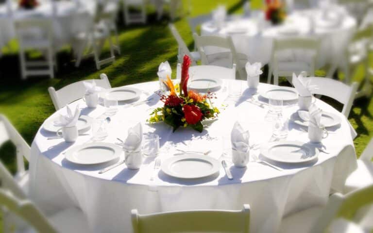 Banquet table on the lawn with red floral centerpiece and white linen