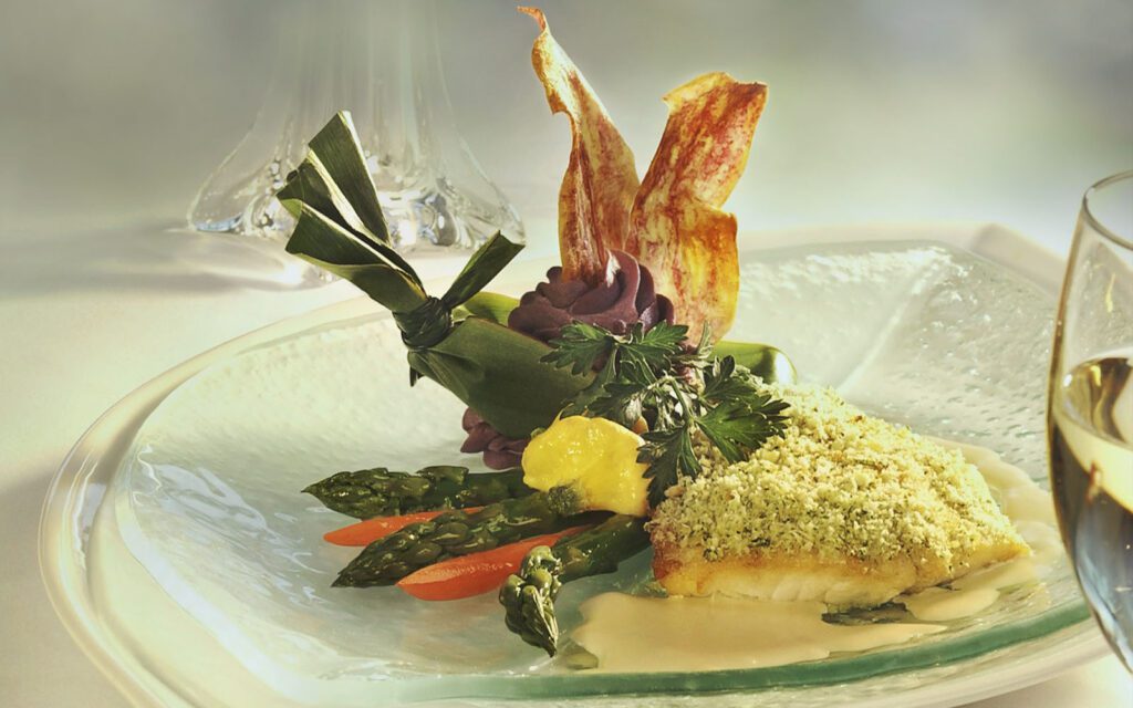Mahimahi fish dish plated on clear glass plate with asparagus, carots, ube mash potatoes and taro chips
