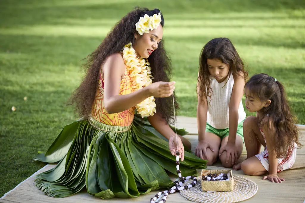 Instructor teaching girls to make a kukui nut lei